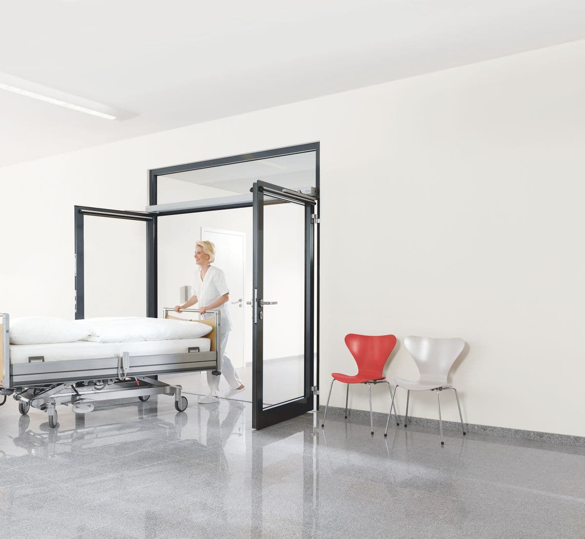 Vrouw loop met ziekenhuisbed door automatische deur